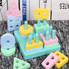 Collection de blocs de construction Montessori en bois colorés et tours dans des tons pastel (rose, jaune, bleu et vert).