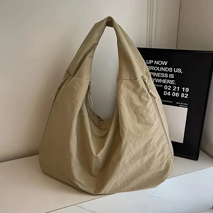 A beige lightweight nylon tote bag with a secure zipper closure is displayed on a white surface.