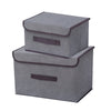A set of two gray fabric storage boxes with dark brown trim for closet and drawer organization.
