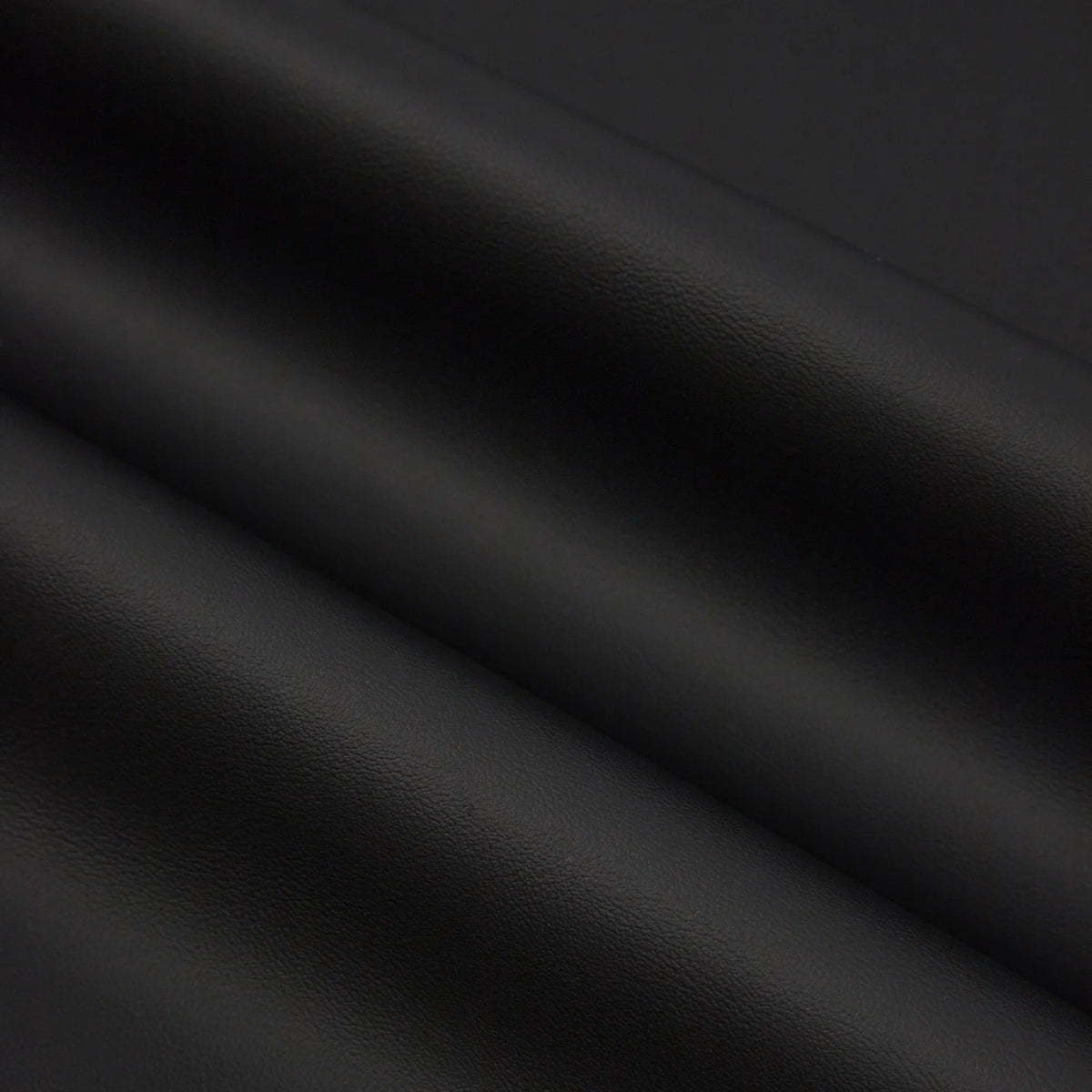 Dark gray faux leather sheets draped and folded, showing texture and subtle sheen.