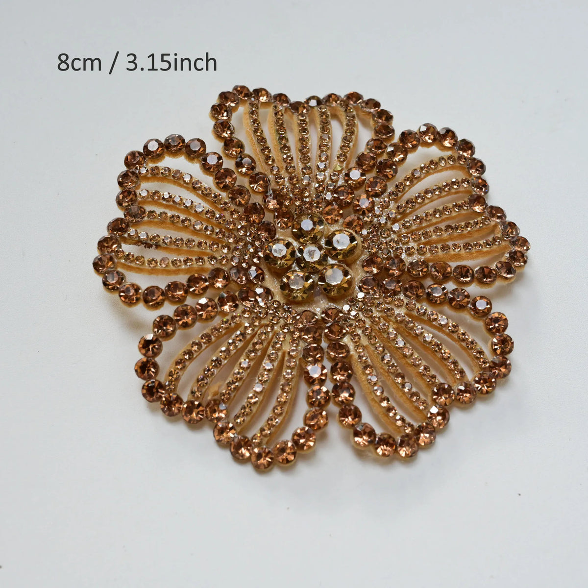 A close-up of a round, textured gold crystal rhinestone flower sew-on patch for clothing and accessories.