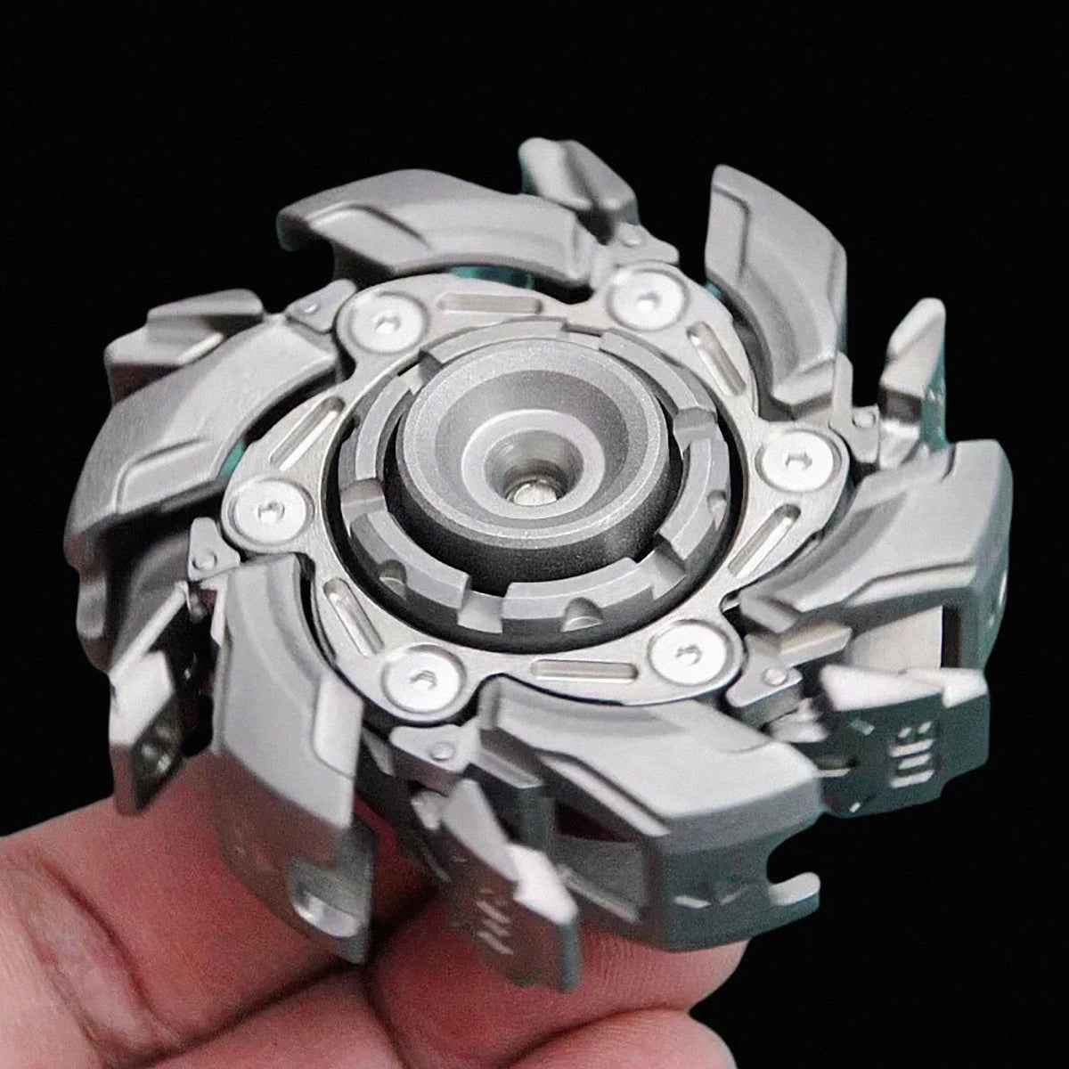 A hand holds a sleek stainless steel fidget spinner with multiple rotating blades.