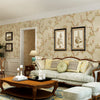 A living room features a sofa and wooden coffee table against a wall covered in floral self-adhesive wallpaper.