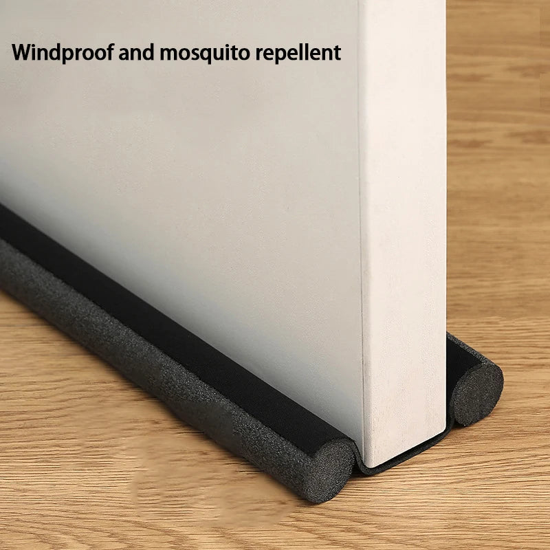 A close-up view of a flexible door bottom seal strip, black and white, shown against a wooden background.
