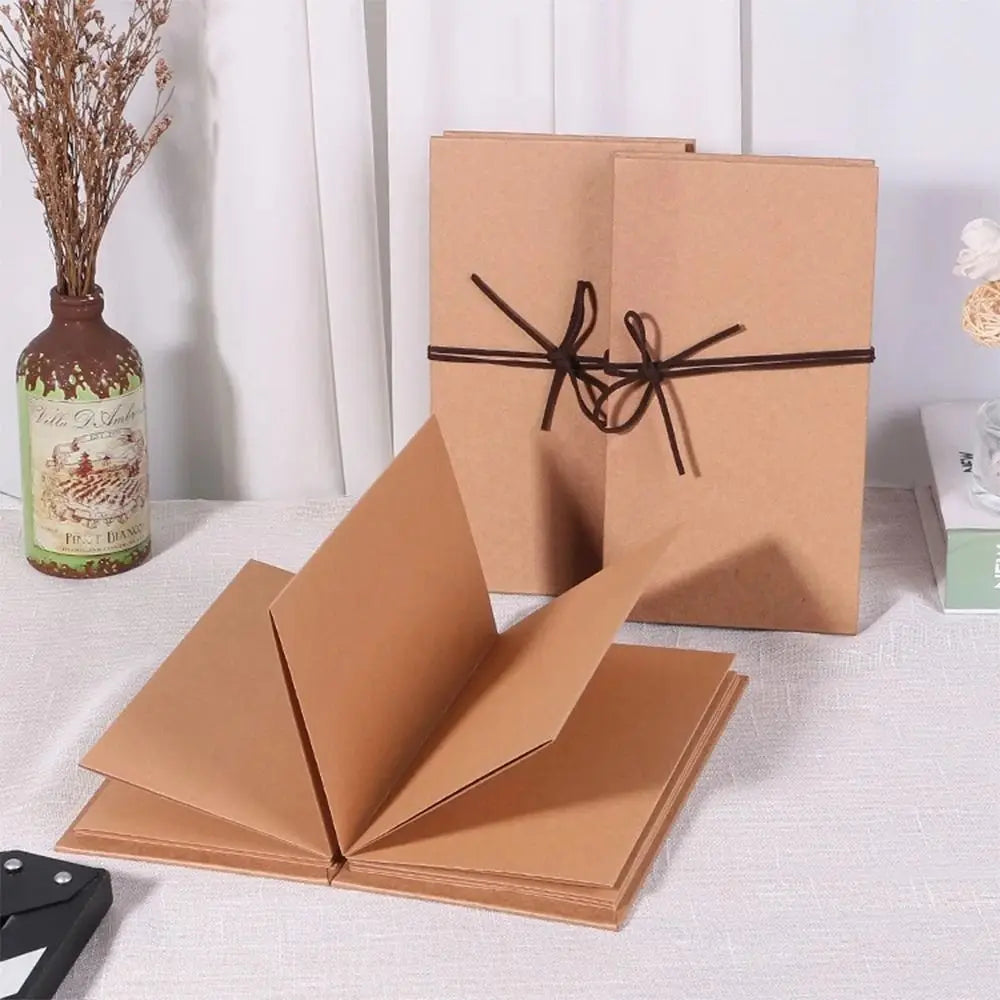 Ein Set aus Kraftpapier-Fotobüchern und eine Glasflasche mit getrockneten Blumen.