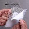 A hand peels off a white, mesh-like self-adhesive drywall repair patch from a piece of paper.