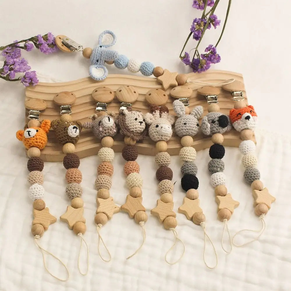 A wooden pacifier clip with crochet beads and animal charms strung on a chain for baby teething.