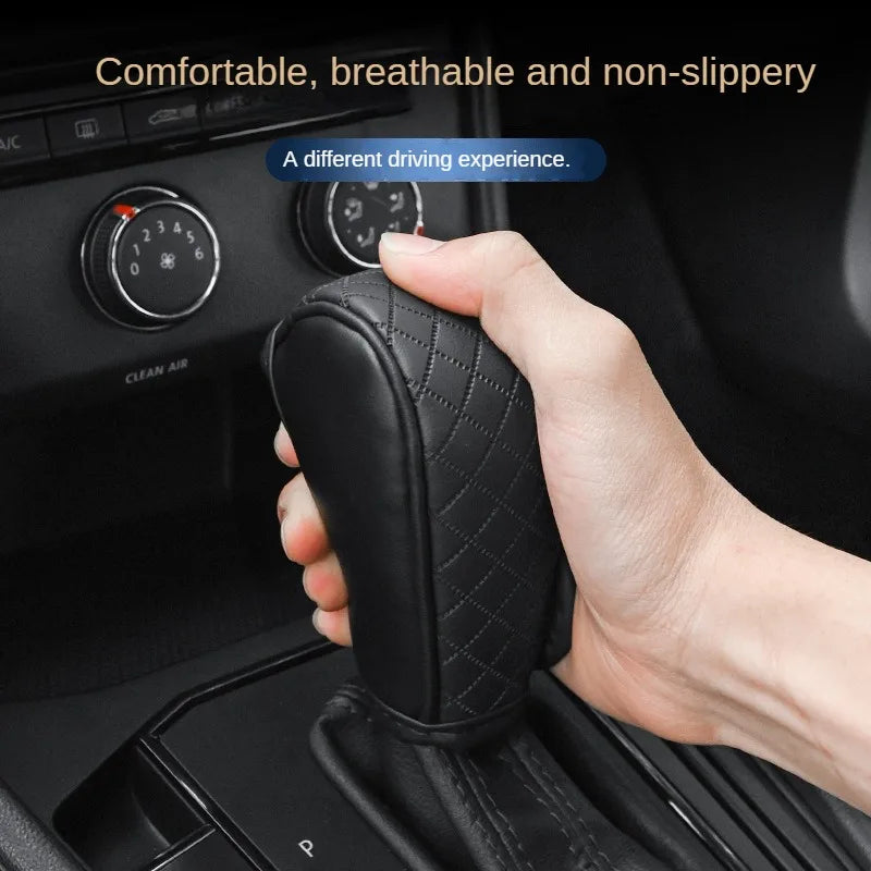 A hand is holding a black PU leather car gear shift cover with diamond stitching.