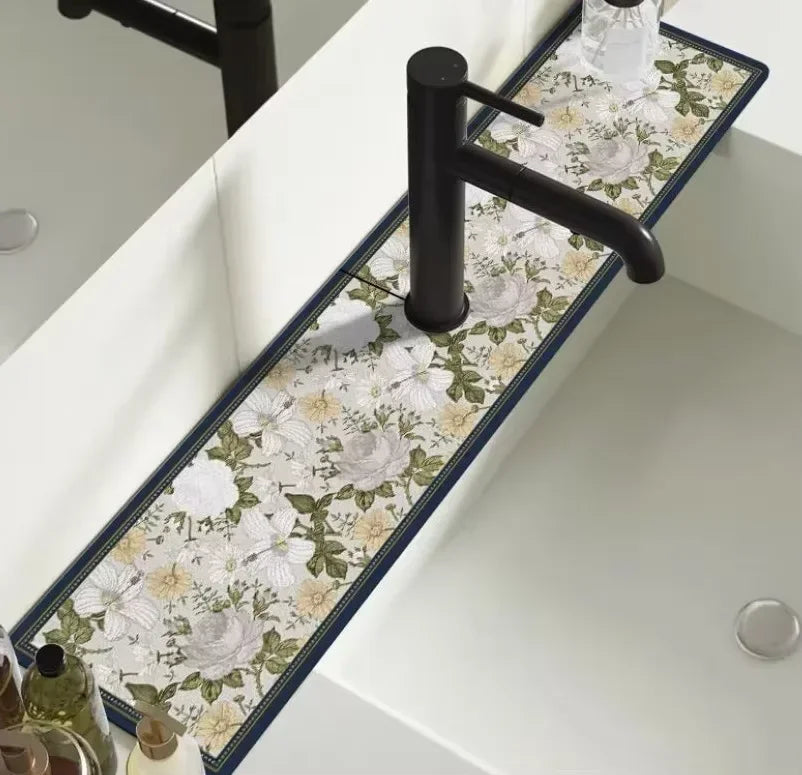 A black faucet mounted on a white countertop with a floral patterned mat featuring white and green roses.