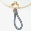 Gold chain necklace with a silver-toned pendant and a gray braided leather fob cover.