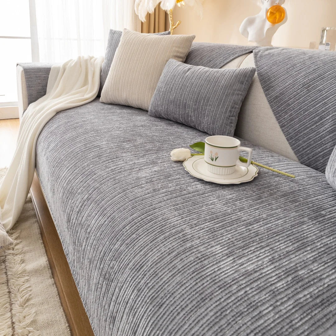 A gray geometric sofa cushion cover with light beige pillows and a white cup on the fabric.