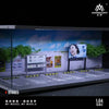A 1:64 scale miniature garage diorama kit featuring a building facade and vehicle display.