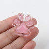 A hand holds a translucent pink squishy cat paw fidget toy with five padded toe shapes.