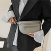 A person wearing a black blazer and striped shirt holds a light gray multi-pocket PU leather waist bag.