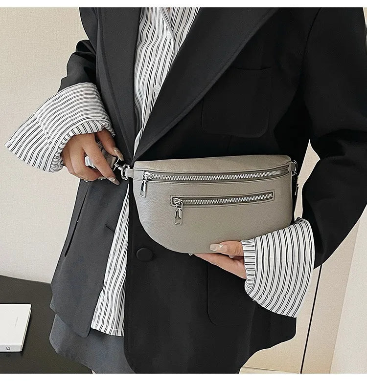 A person wearing a black blazer and striped shirt holds a light gray multi-pocket PU leather waist bag.