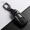A black carbon fiber style key fob cover with a silver keyring and electronic components.