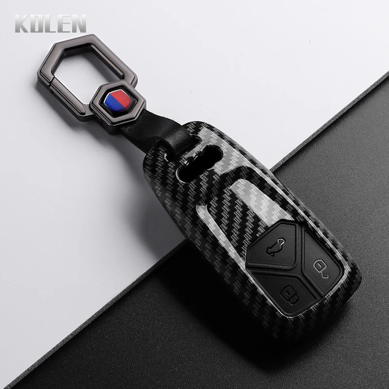 A black carbon fiber style key fob cover with a silver keyring and electronic components.