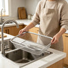 A person is using a stainless steel garden soil sieve for potting and plant care in a kitchen sink.