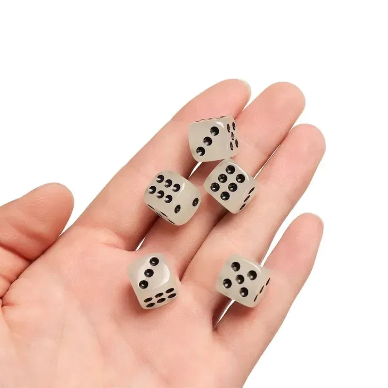 A hand holds a set of glow-in-the-dark acrylic dice for night games.