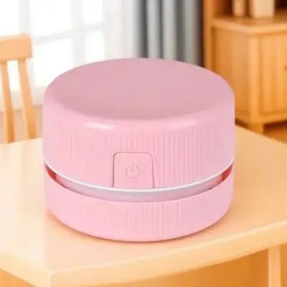 Pinkes Mini-Tischstaubsauger mit runder Ober- und Unterseite auf Holzoberfläche