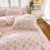 Pink floral ruffle cotton duvet cover set displayed on a bed with white wooden storage drawers and sheer curtains.