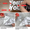 Hand applying a vinyl sticker transfer film onto backing paper for a custom name motorcycle helmet decal.