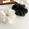 A pair of black and white polka dot mesh scrunchie hair ties displayed on a white surface.