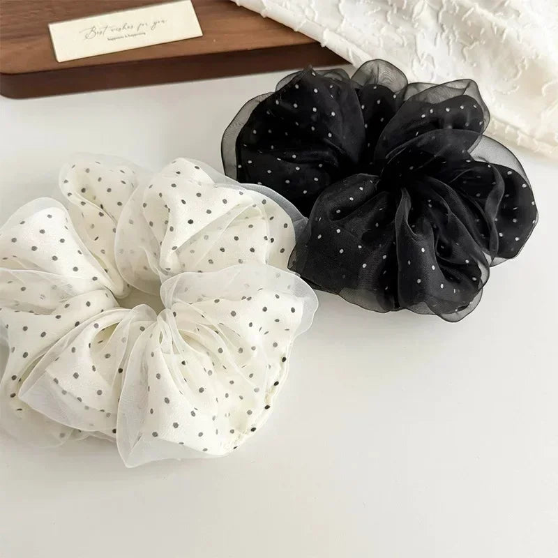 A pair of black and white polka dot mesh scrunchie hair ties displayed on a white surface.