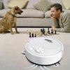 A white robot vacuum cleaner is shown on a light carpet in a living room setting.