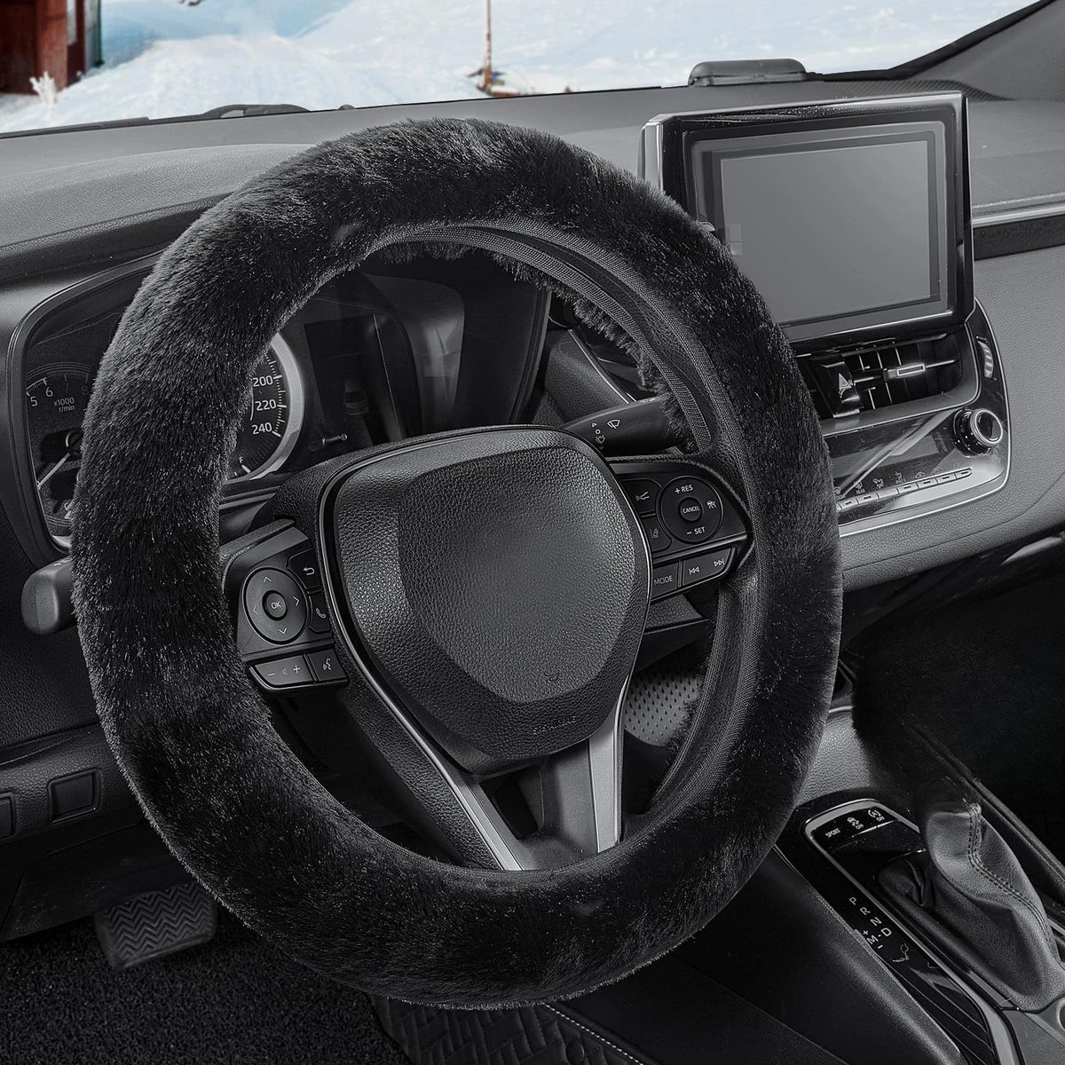 Interior view of a car showing a black fuzzy steering wheel cover and infotainment screen.