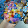 Klare Schale gefüllt mit farbenfrohen Regenbogenperlen, verwendet als quietschender Stressball
