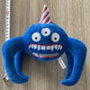 A blue plush toy resembling a bird with a conical striped hat and large eyes.