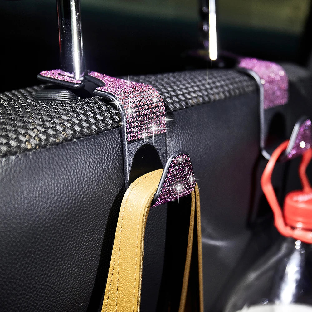 A black car seat storage hook set featuring crystal diamond accents and a tan leather strap.