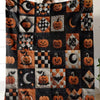 A patchwork throw blanket featuring orange pumpkins and crescent moons on a black fabric.