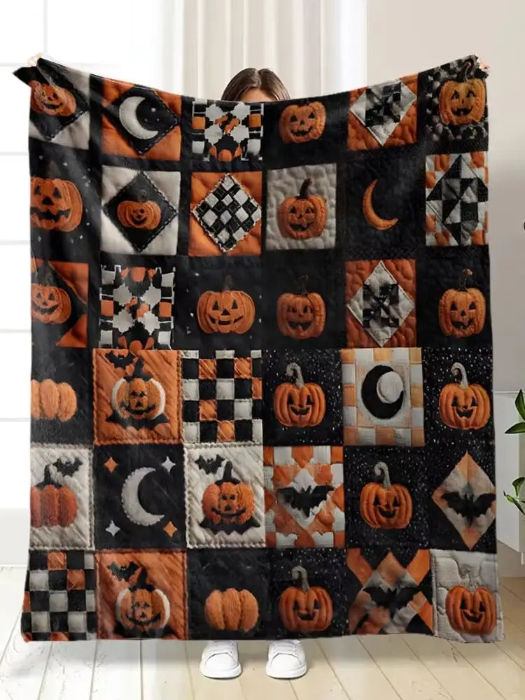 A patchwork throw blanket featuring orange pumpkins and crescent moons on a black fabric.