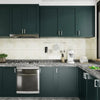 A modern kitchen cabinet and countertop featuring dark green cabinetry and light beige countertops.