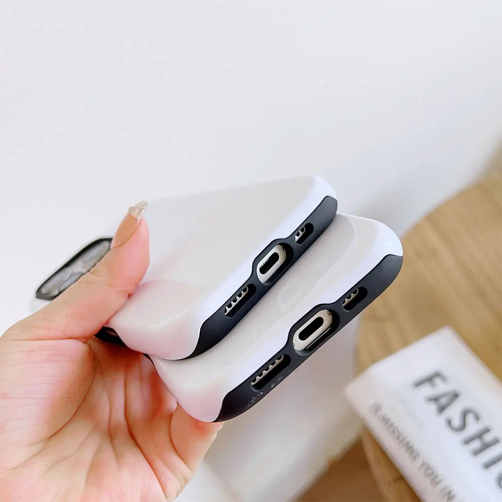 A hand holds a white dual-layer phone case for an iPhone with black accents.