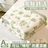 A stack of white quilted bedding with green floral patterns, marketed as an ultra-light breathable summer quilt.
