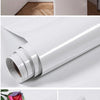 Roll of white pearl waterproof self-adhesive marble wallpaper shown in various angles.