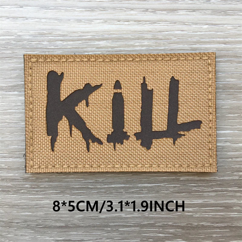 A brown woven patch with the word KILL embossed in dark silhouette on a light wooden background.