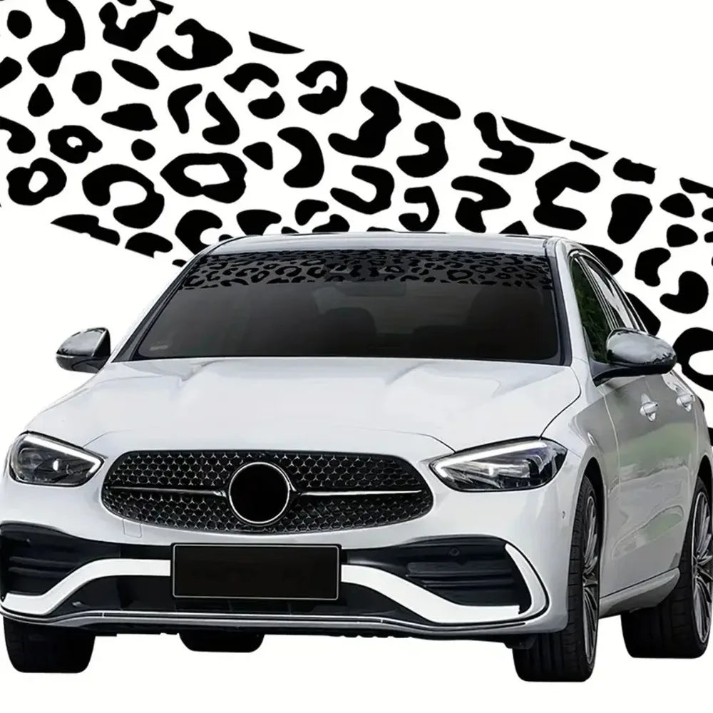 White car with a black leopard print sunshade decal strip on the windshield.