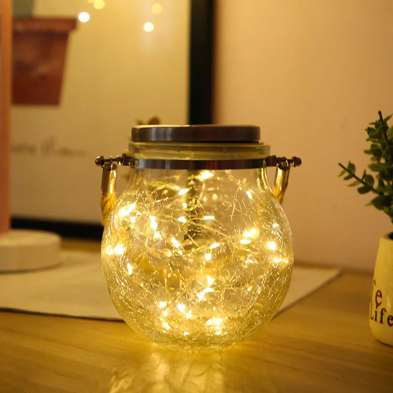 A glass solar lantern with a warm ambient glow sits on a wooden surface.