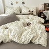 A white duvet cover set with black polka dots is displayed on a bed, alongside pillows and a stuffed animal.