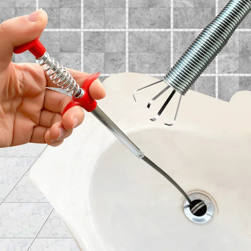 A hand is using a drain unclogging tool with an ergonomic handle to clear a sink drain.