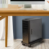 A dark gray adjustable rolling CPU stand with wheels is positioned under a wooden desk.