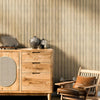 A wooden dresser with drawers and a chair sits against a vertical wood grain wall panel.