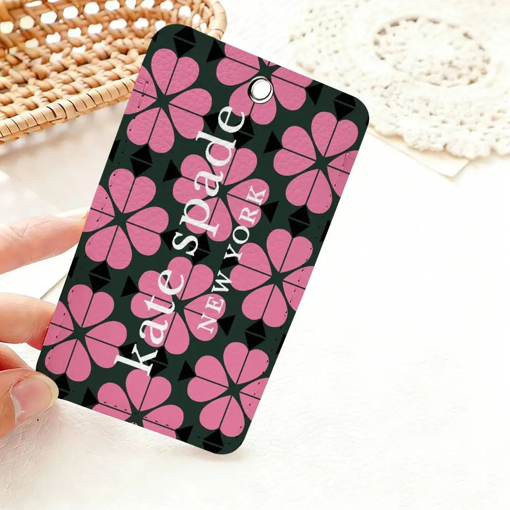 A pink and black floral pattern card holder featuring the name Kate Spade New York