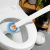 A white toilet with a white wall-mounted brush holder and blue cleaning brush visible inside the bowl.