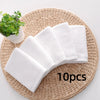 Ten white soft cotton terry cloth face towels arranged on a woven mat.