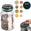 A clear glass jar filled with coins and a digital coin counting piggy bank with an LCD display and various coins.